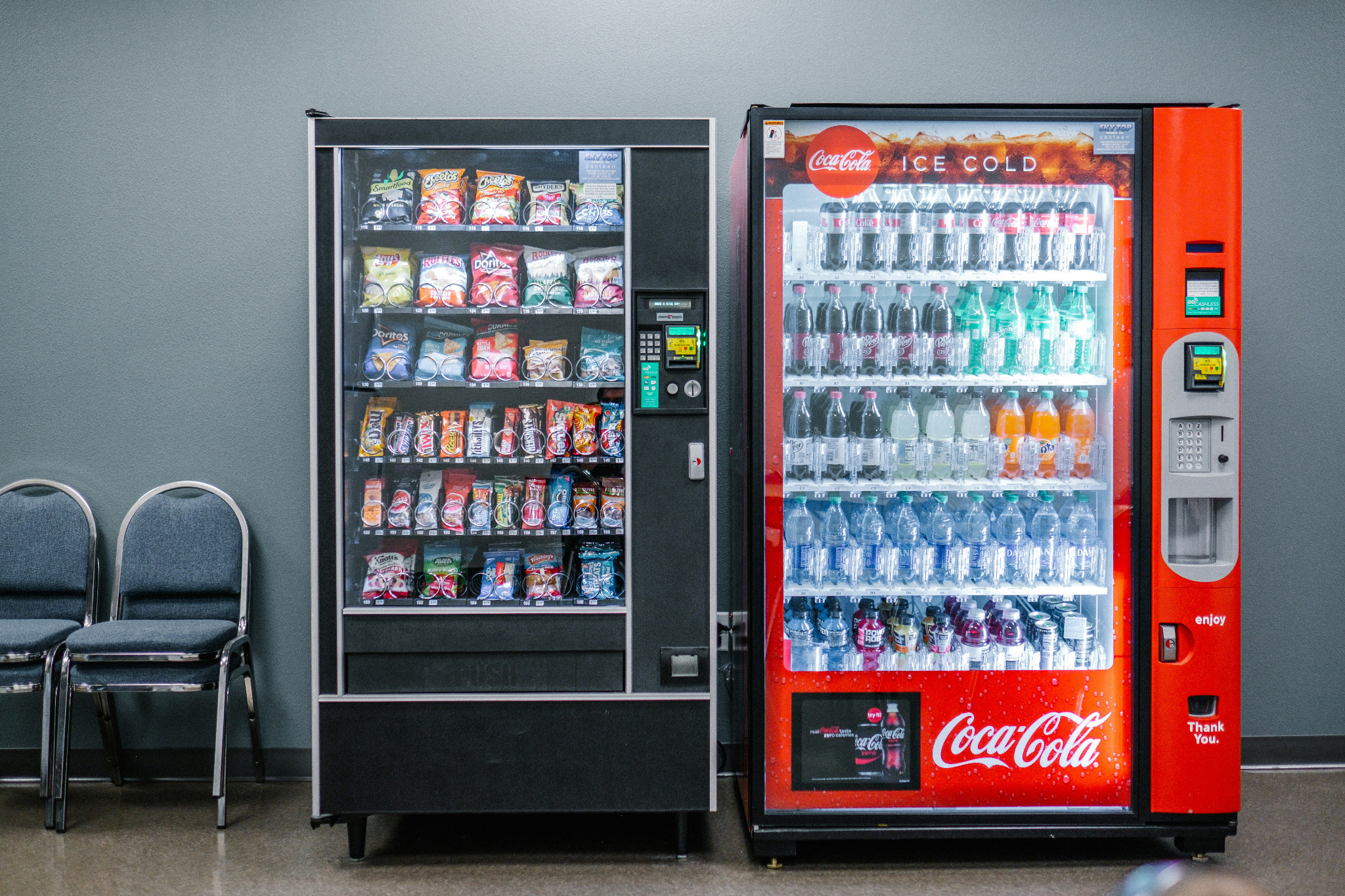 Stocked snack machine beside a basic drink vending machine